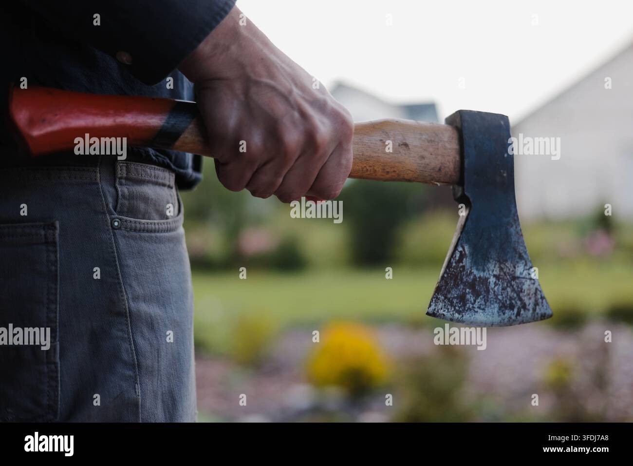 gros plan d'un homme tenant une hache à l'extérieur, créant un concept de scène de crime sombre associé à la violence, à la menace, à l'agression et au danger criminel. Banque D'Images