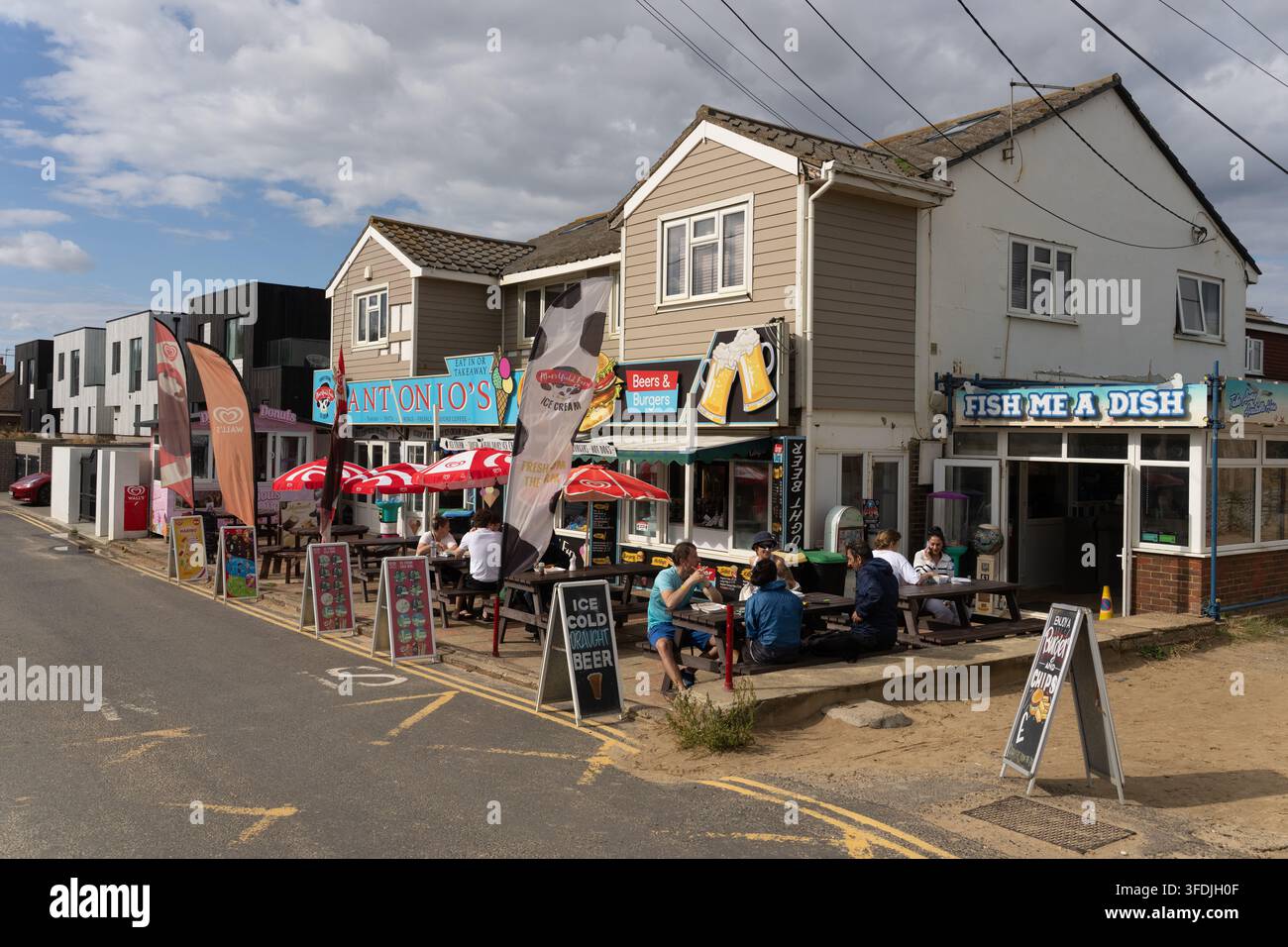 Les clients dînent à l'extérieur des cafés Antonio's et Fish Me A Dish à Camber Sands, dans l'East Sussex, profitant de nourriture et de boissons au bord de la plage. Banque D'Images