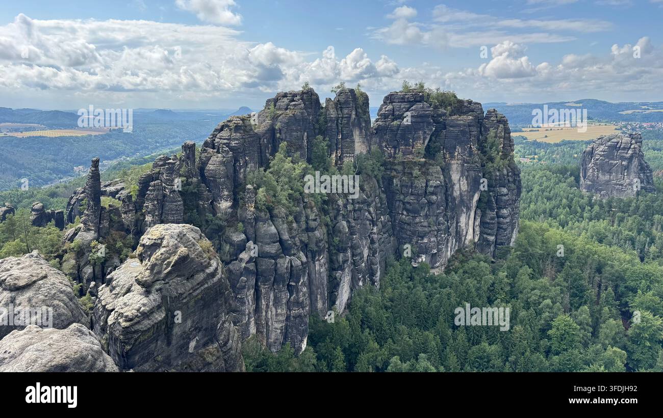 Vue panoramique estivale des falaises de grès escarpées et des vallées boisées depuis le point de vue des Schrammsteine en Saxe, Allemagne. - Image de stock capturée avec un smartphone