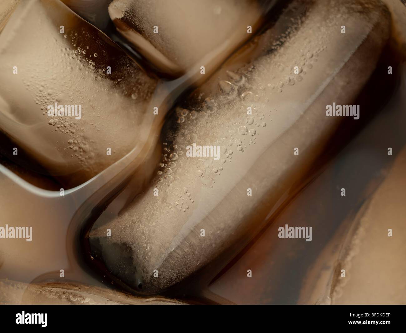 Macro rapprochée de glaçons flottant dans un soda au cola froid gazeux avec de fines bulles de condensation Banque D'Images