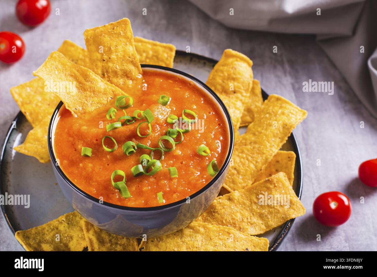 Grossissement d'un bol de sauce salsa mexicaine aux tomates avec herbes et chips de maïs sur la table Banque D'Images