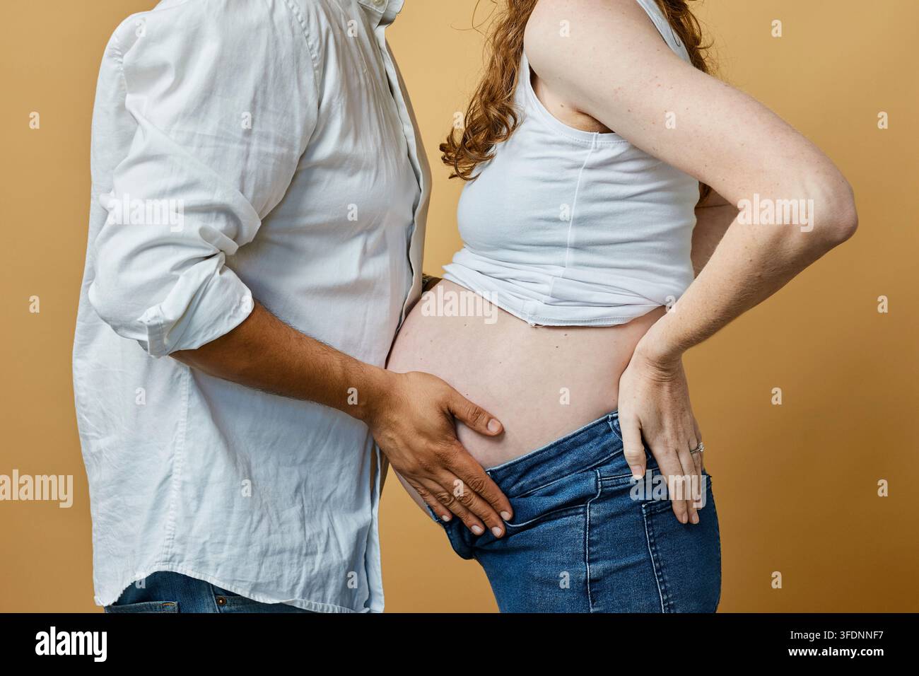 Couple enceinte embrassant le ventre enceinte lors d'une séance photo maternité intime avec des touches d'amour Banque D'Images