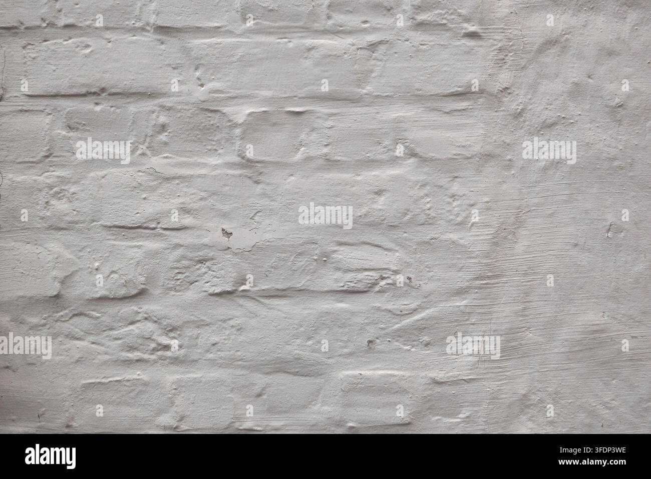 Vue rapprochée d'un mur de briques blanchi avec une peinture inégale révélant la maçonnerie et une subtile altération créant un fond texturé neutre dans le Brug historique Banque D'Images