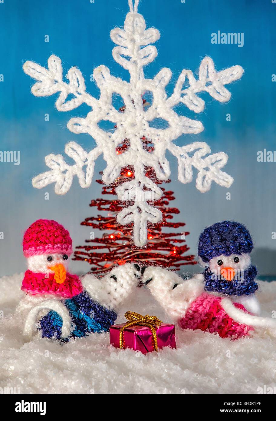 Des souris et des bonhommes de neige crochetés à la main sous un délicat flocon de neige crocheté, créant une scène de Noël réconfortante dans la neige Banque D'Images