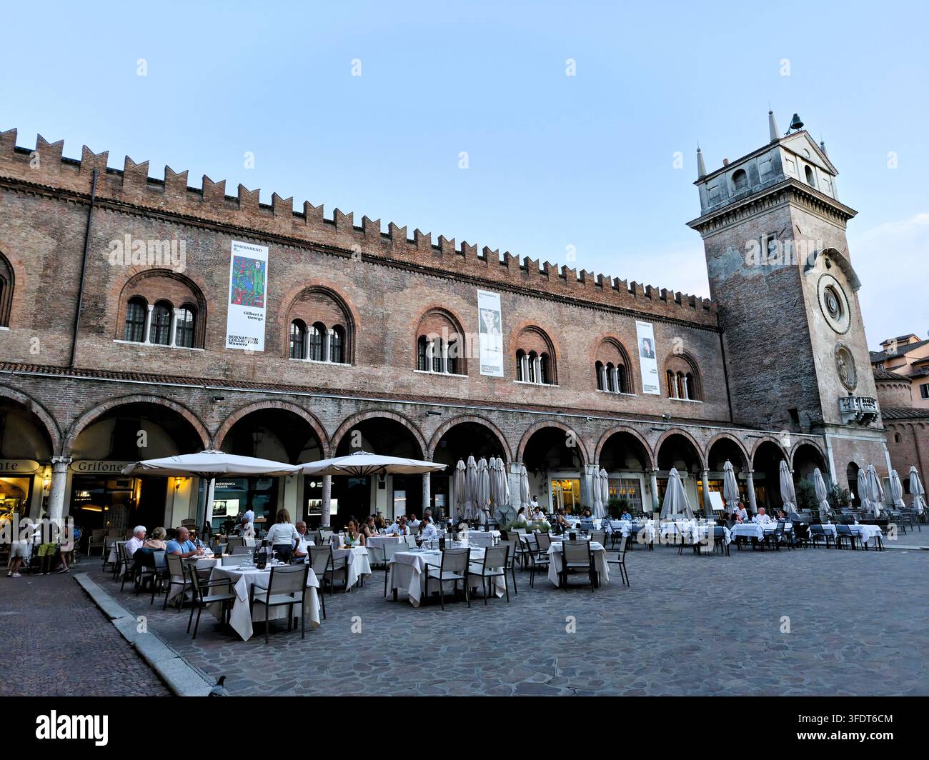 Mantoue Piazza delle Erbe montrant les arcades du Palazzo della Ragione avec des affiches de la collection Sonnabend, des cafés de rue et la tour de l'horloge en Italie - Image de stock capturée avec un smartphone