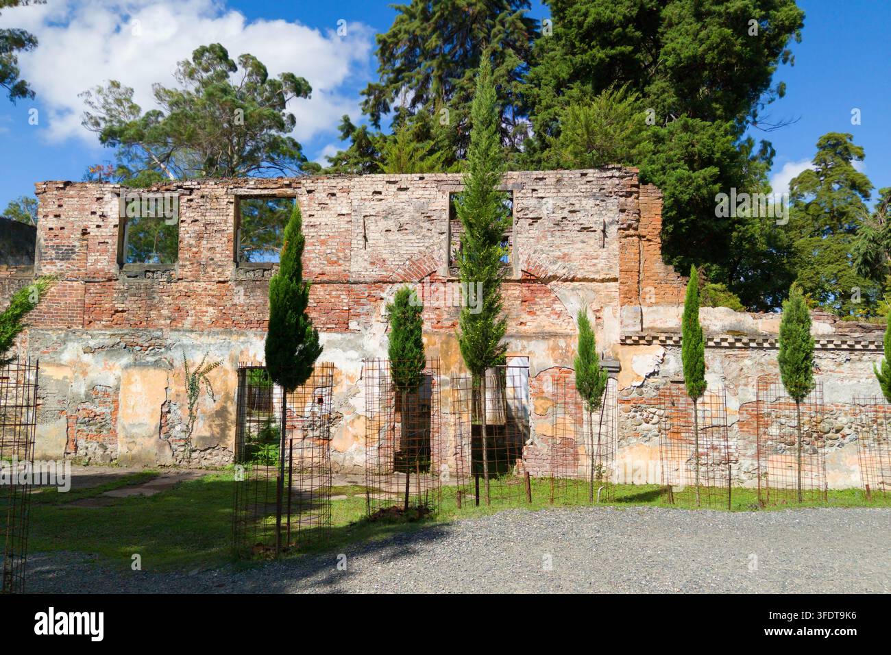 Une prise de vue en plein jour d'une vieille façade de bâtiment en ruine faite de briques rouges et de pierre érodée. La structure présente un cadre de fenêtre rectangulaire vide Banque D'Images