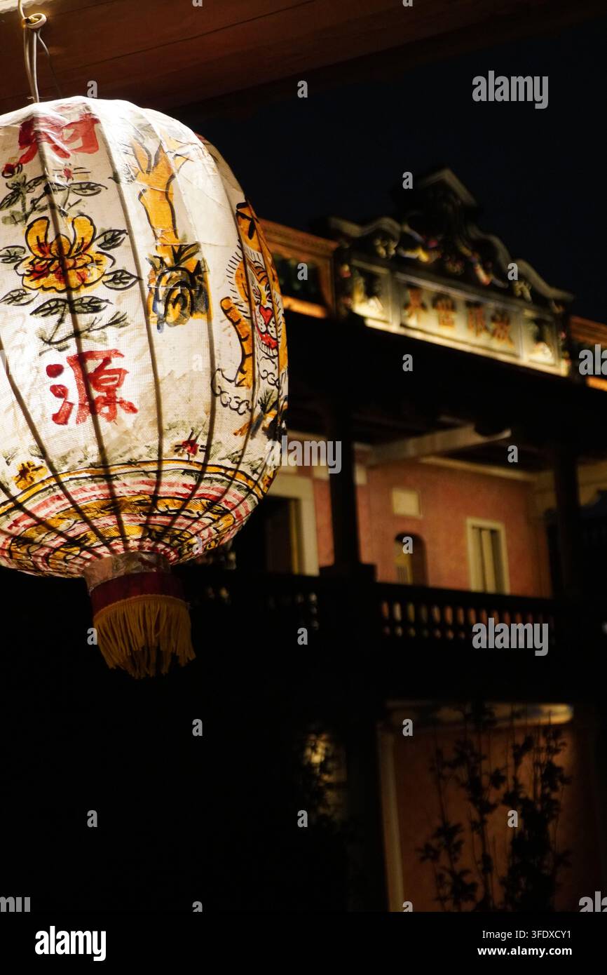 Lanterne en papier blanc avec des caractères japonais suspendue devant un bâtiment illuminé la nuit à Tokyo, Japon Banque D'Images