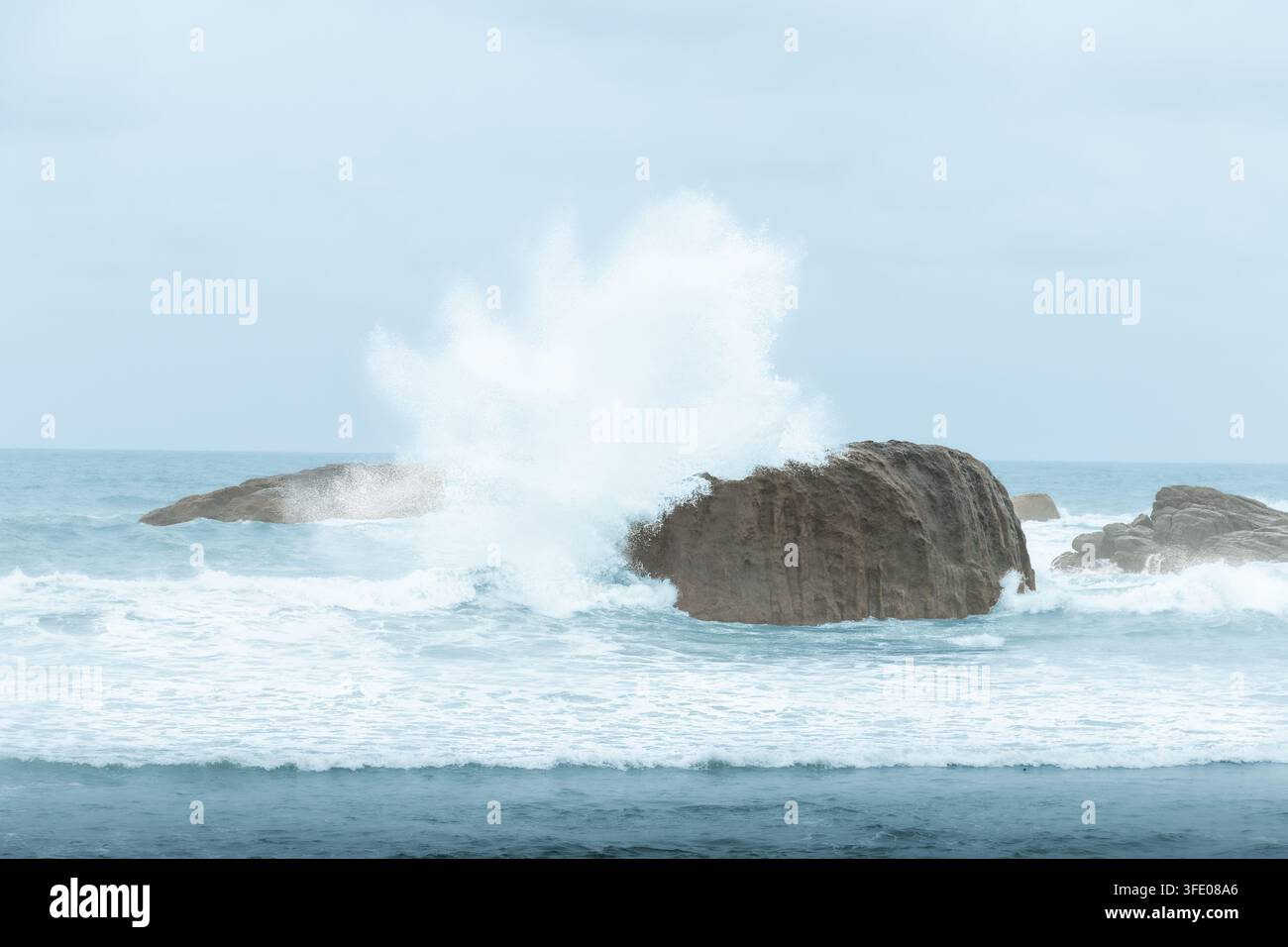 Vague haute de la mer s'écrasant contre une formation rocheuse massive, envoyant un spray d'écume blanc dramatique dans l'air sur la côte sauvage de l'océan Indien au Sri Lanka Banque D'Images