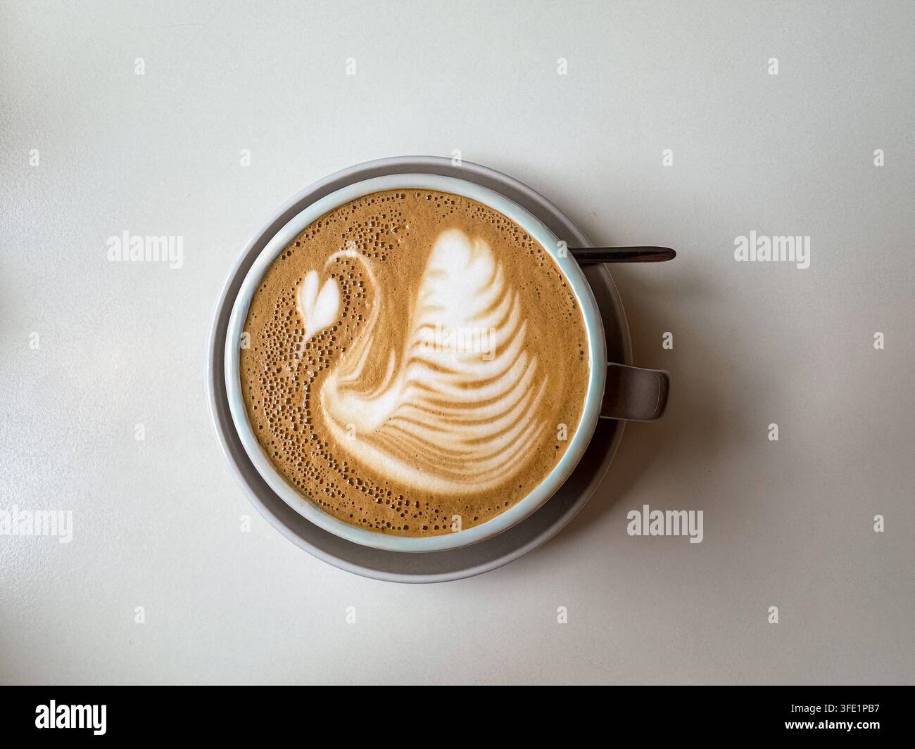 Art latte en forme de cygne dans une tasse de café sur une table minimaliste légère, photographiée de dessus avec espace de copie. - Image de stock capturée avec un smartphone