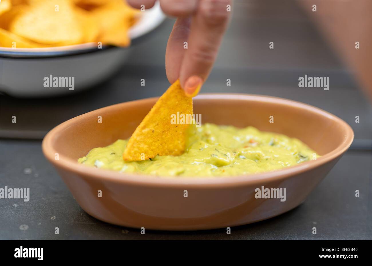 Une chip tortilla plongeant dans de la guacamole fraîche Banque D'Images