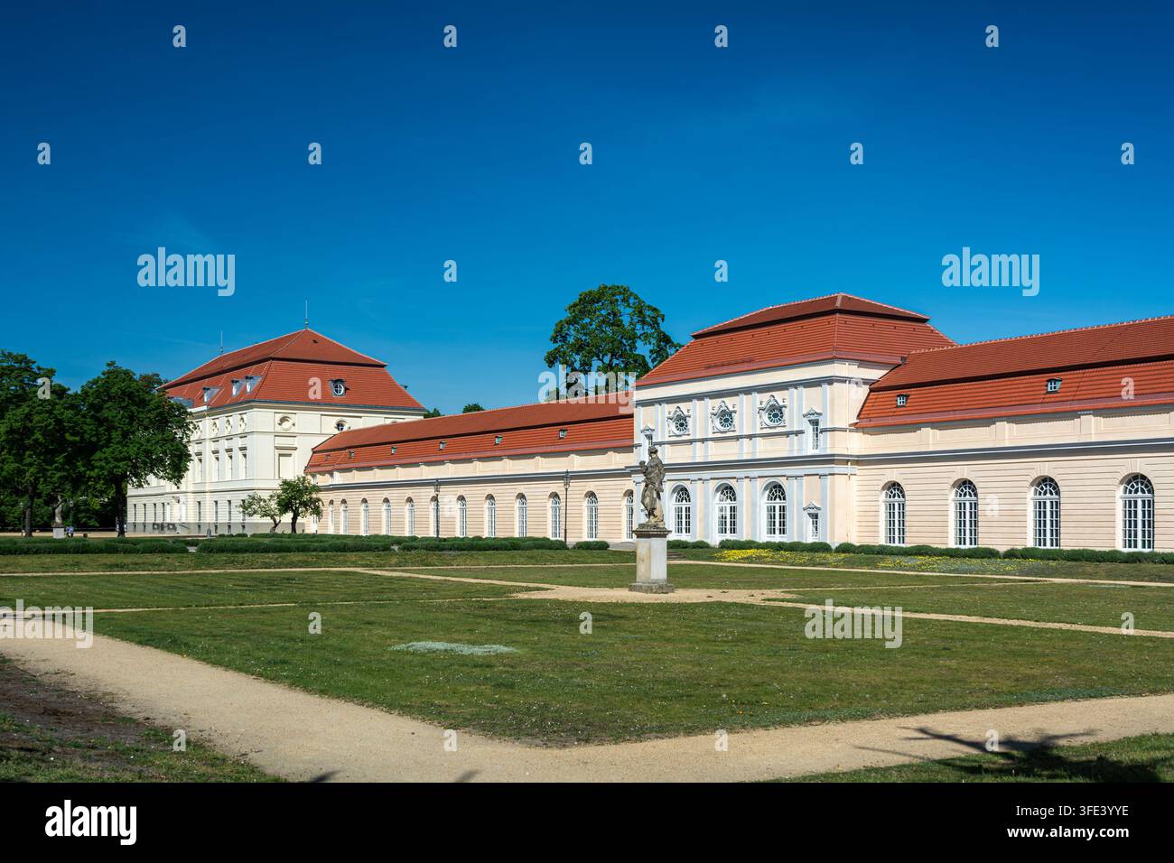 Vue large de la Grande Orangerie du palais de Charlottenburg à Berlin, montrant sa longue façade baroque, ses toits aux tuiles rouges, sa pelouse de jardin et sa sculpture historique Banque D'Images
