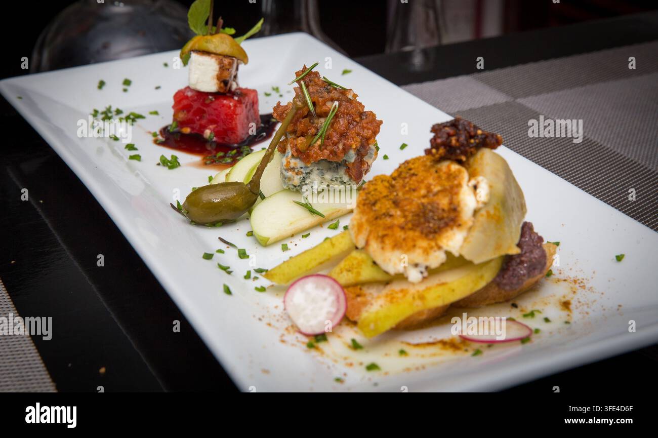 Une photographie en gros plan mettant en valeur trois hors-d'œuvre gastronomiques magnifiquement présentés, dont une pile de pastèque et feta ainsi que des associations fromage-fruits, élégamment a Banque D'Images