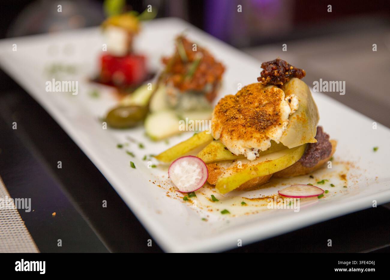 Une photographie en gros plan mettant en valeur trois hors-d'œuvre gastronomiques magnifiquement présentés, dont une pile de pastèque et feta ainsi que des associations fromage-fruits, élégamment a Banque D'Images