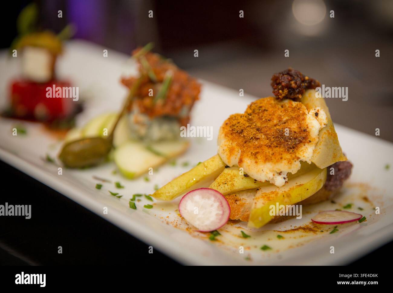 Une photographie en gros plan mettant en valeur trois hors-d'œuvre gastronomiques magnifiquement présentés, dont une pile de pastèque et feta ainsi que des associations fromage-fruits, élégamment a Banque D'Images