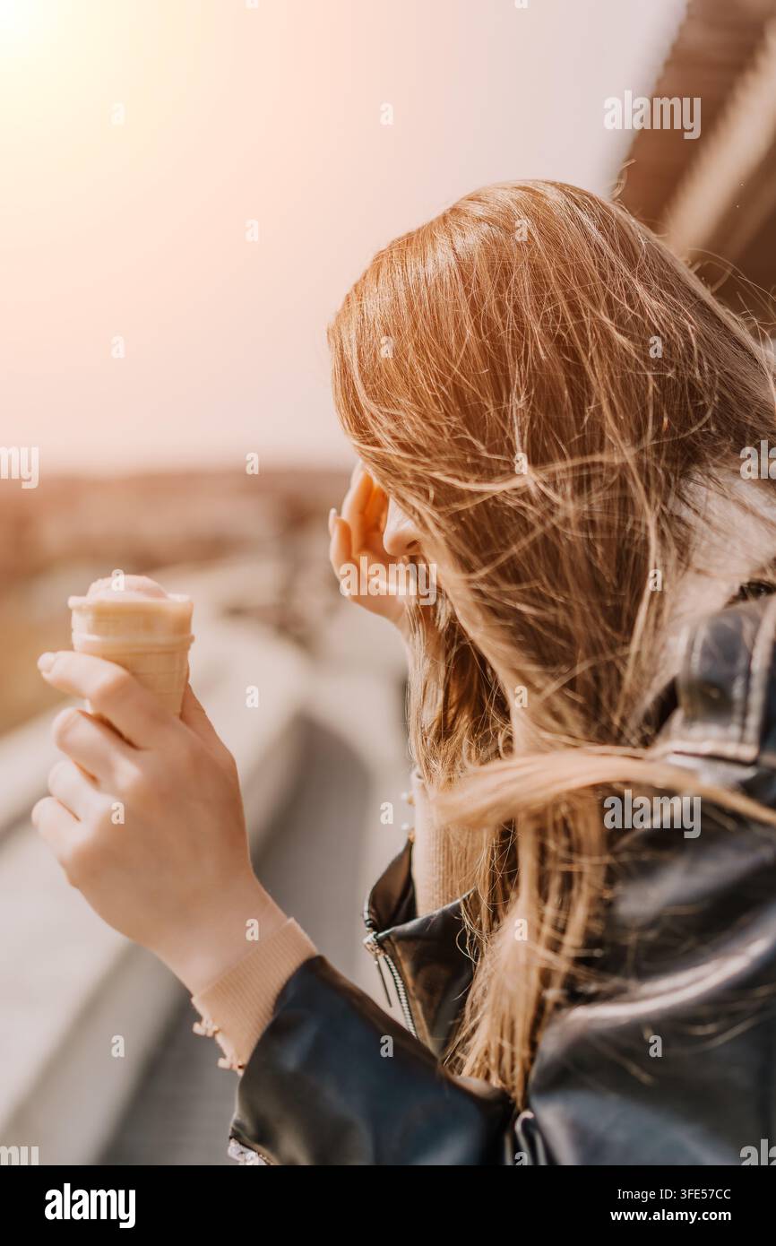Femme dessert cheveux jeune femme aux longs cheveux flottant au vent tenant une glace à l’extérieur au coucher du soleil avec espace de copie Banque D'Images