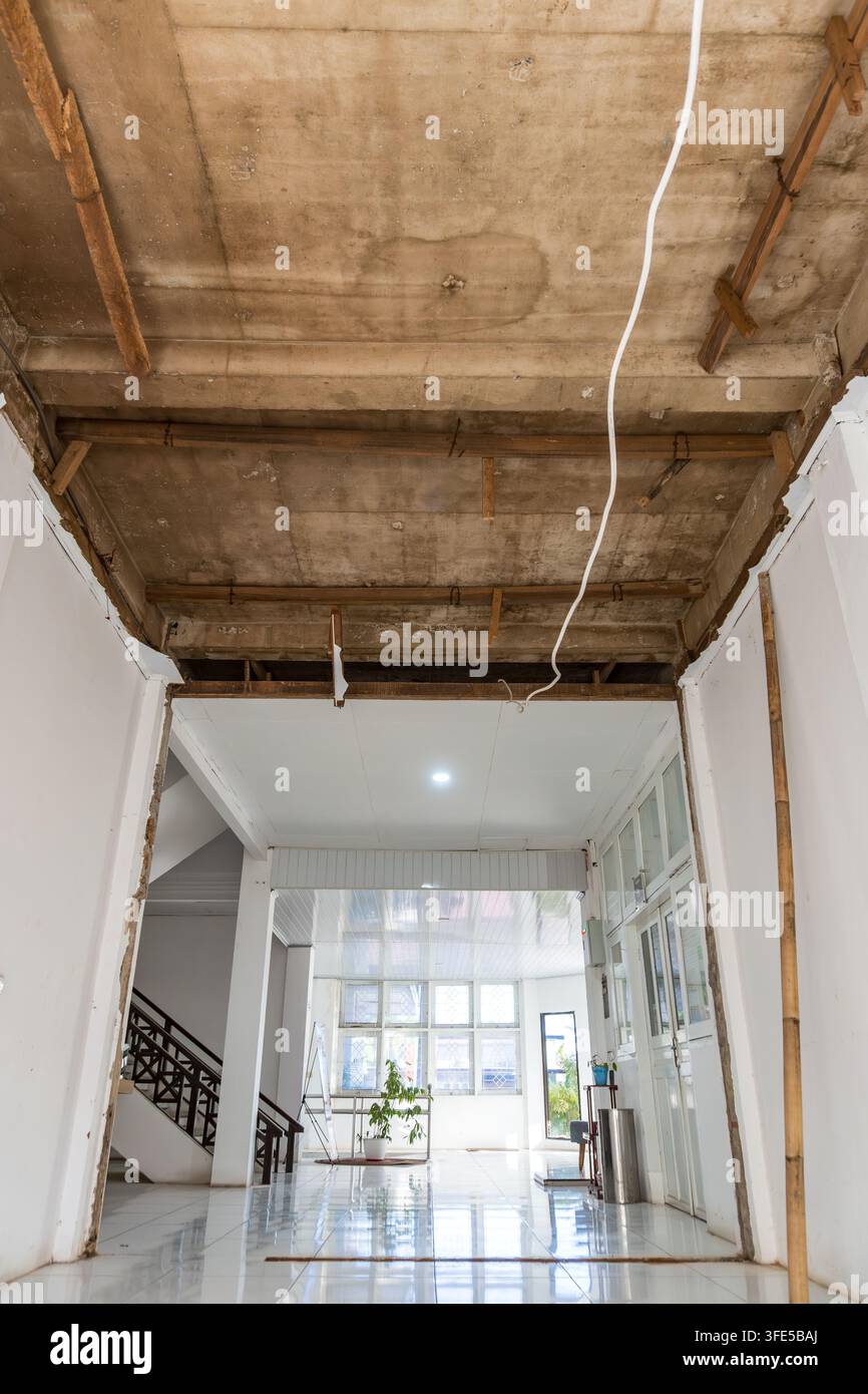 Couloir intérieur en rénovation avec plafond en béton apparent et supports en bois Banque D'Images