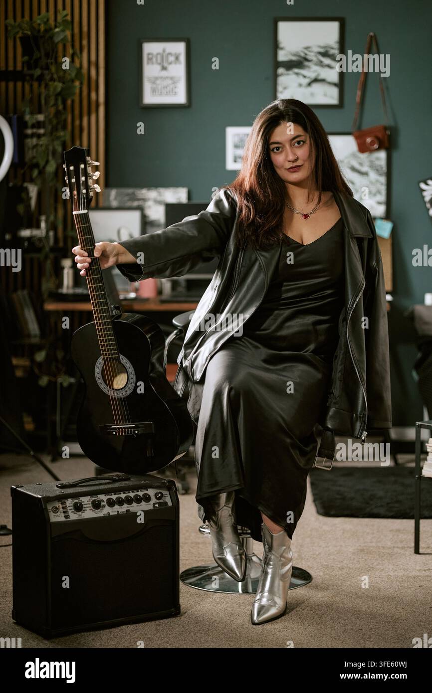Portrait d'une musicienne tenant une guitare dans un studio de musique Banque D'Images