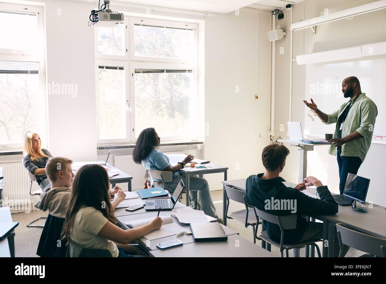 Professeur masculin expérimenté expliquant une formule mathématique à des élèves adolescents dans une salle de classe au lycée Banque D'Images