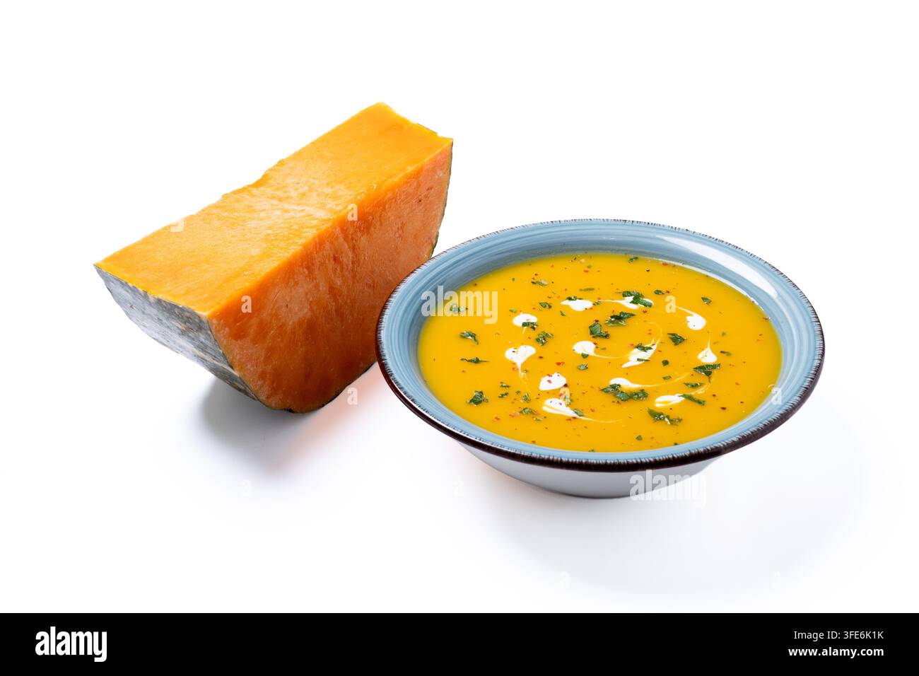 Soupe crémeuse de citrouille aux herbes et à la crème dans un bol bleu isolé sur fond blanc Banque D'Images