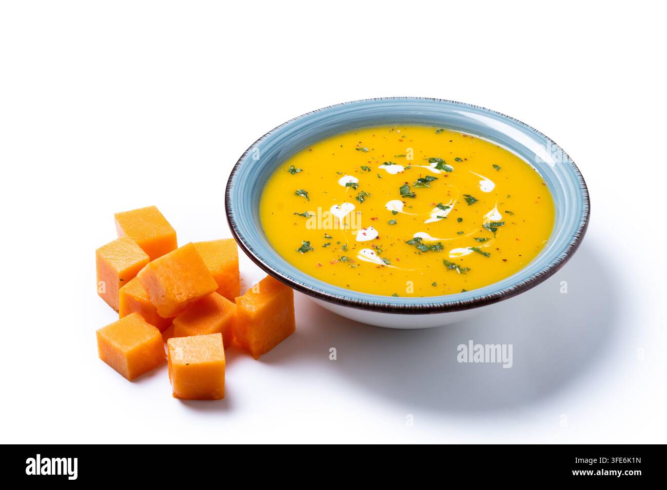 Soupe crémeuse de citrouille aux herbes et à la crème dans un bol bleu isolé sur fond blanc Banque D'Images