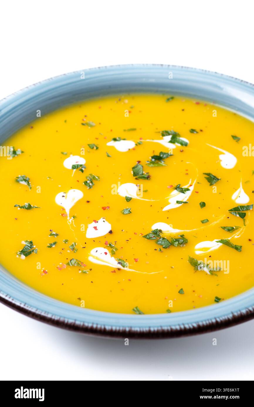 Soupe crémeuse de citrouille aux herbes et à la crème dans un bol bleu isolé sur fond blanc Banque D'Images