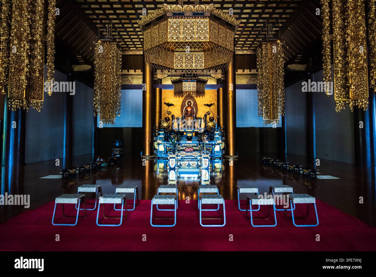 Un autel cérémoniel en or élaboré avec des lanternes suspendues et une statue de Bouddha assise remplit l'intérieur en bois sombre de la salle principale du temple Zojoji. Banque D'Images