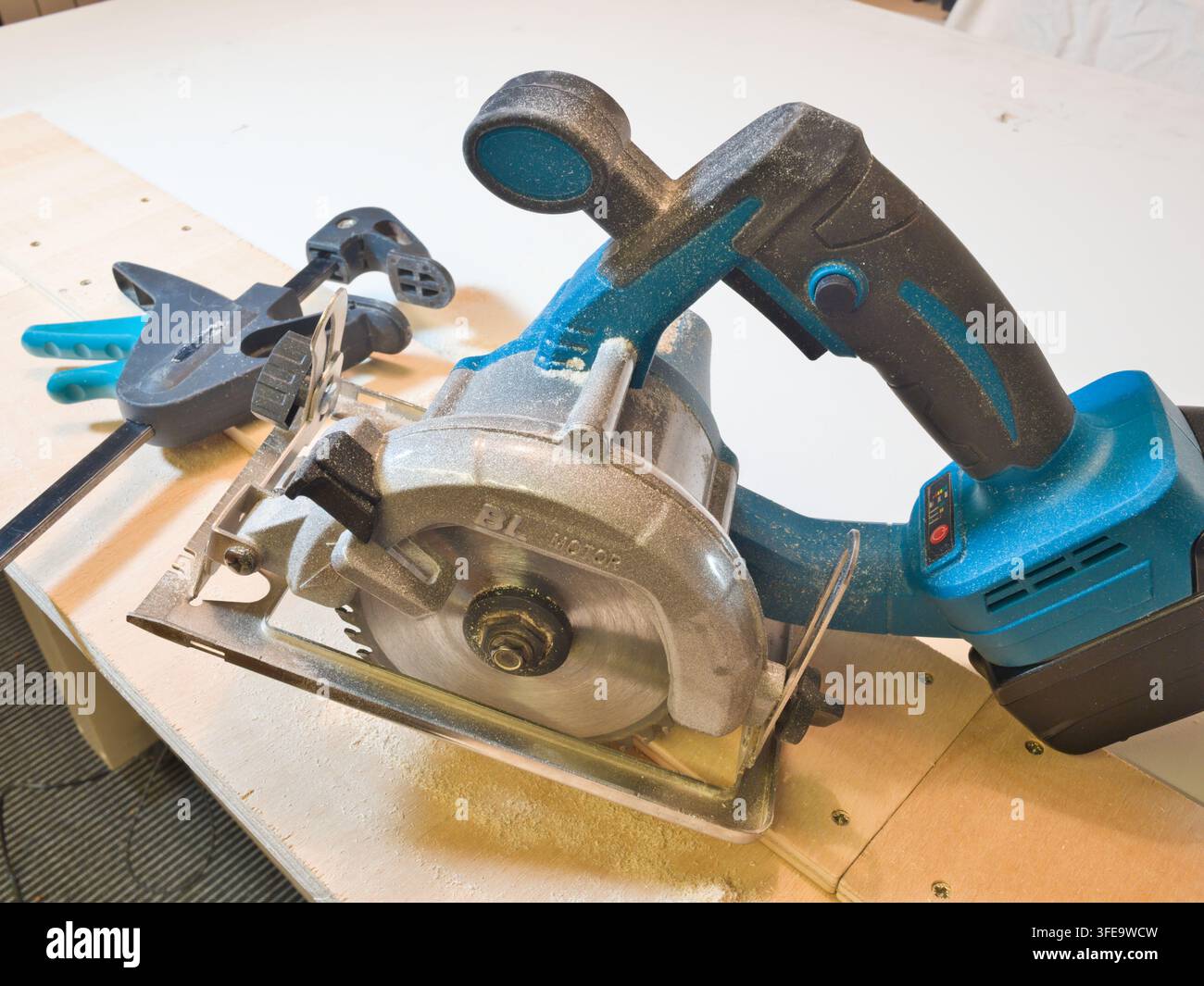 Scie circulaire sans fil coupant du bois - Un charpentier professionnel utilise une scie circulaire portable alimentée par batterie pour couper une planche de bois dans un atelier. Banque D'Images