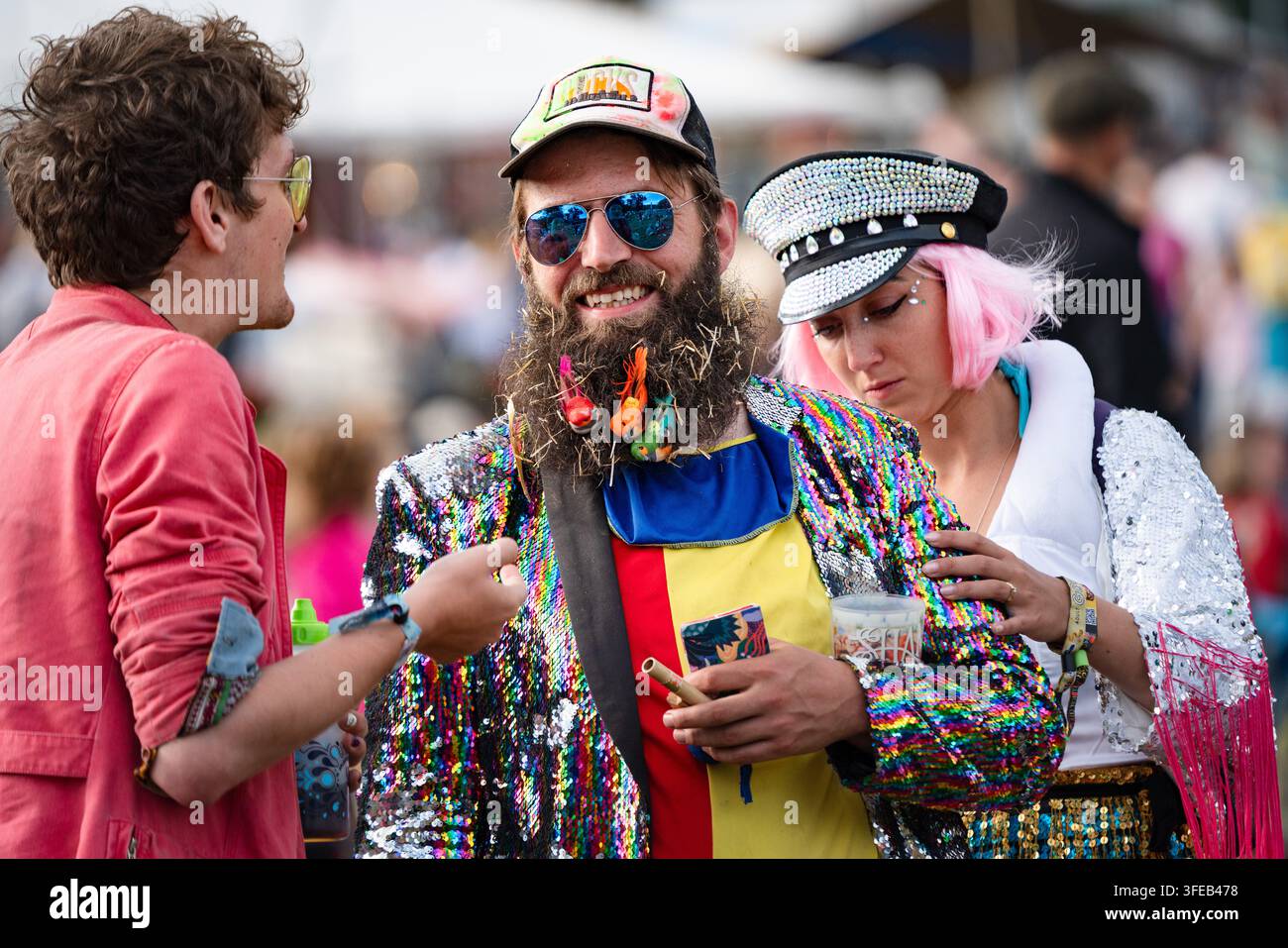AMI(E)S EN TENUES FLAMBOYANTES À UN FESTIVAL, REPORTAGES, GREEN MAN FESTIVAL 2019, BRECON, WALES, UK, 2019 : Un homme barbu vêtu d’une veste à paillettes et une femme aux cheveux roses discutent avec un ami lors d’un festival de musique en plein air. Photo : Rob Watkins. INFO : Le Green Man Festival a commencé en 2003 au Pays de Galles. Il se tient chaque année dans les Brecon Beacons le troisième week-end d’août et célèbre la musique alternative, les arts, la littérature, la science et une culture adaptée aux familles dans un magnifique cadre montagneux. Banque D'Images