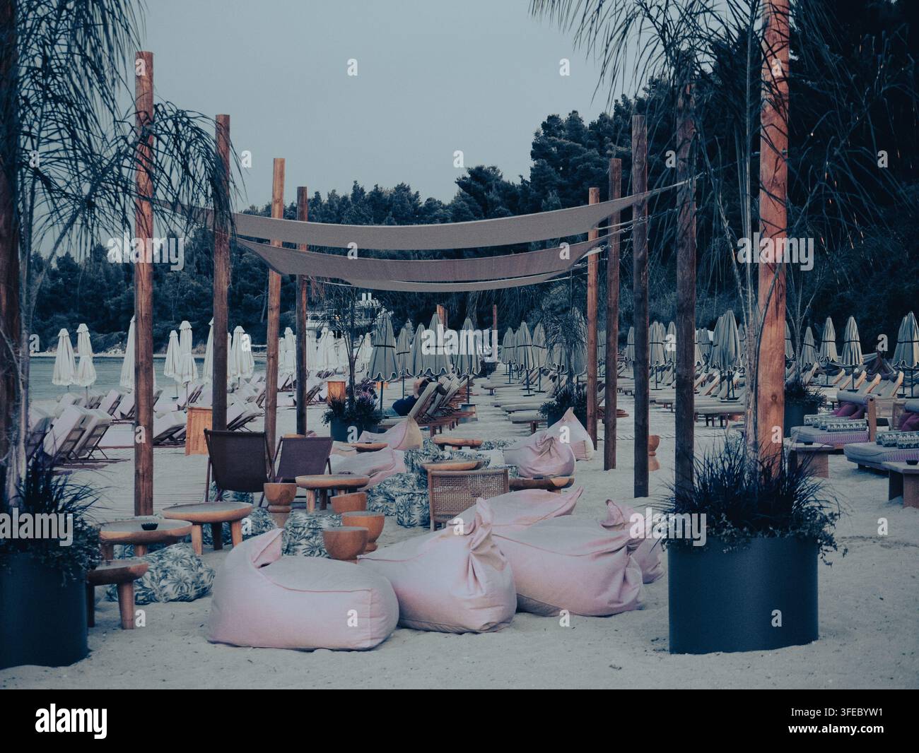 Espace de détente de plage avec des chaises poires roses confortables sous un auvent en tissu sur une plage de sable fin en Grèce au crépuscule. Banque D'Images