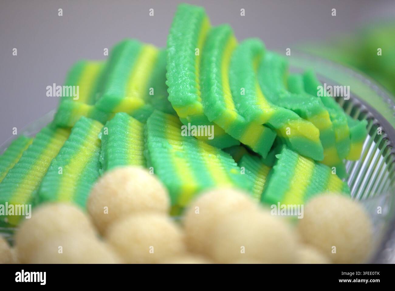 Goûter traditionnel indonésien Getuk Lindri fait de manioc écrasé avec des couches vertes et jaunes, servi dans un contenant en plastique. Banque D'Images
