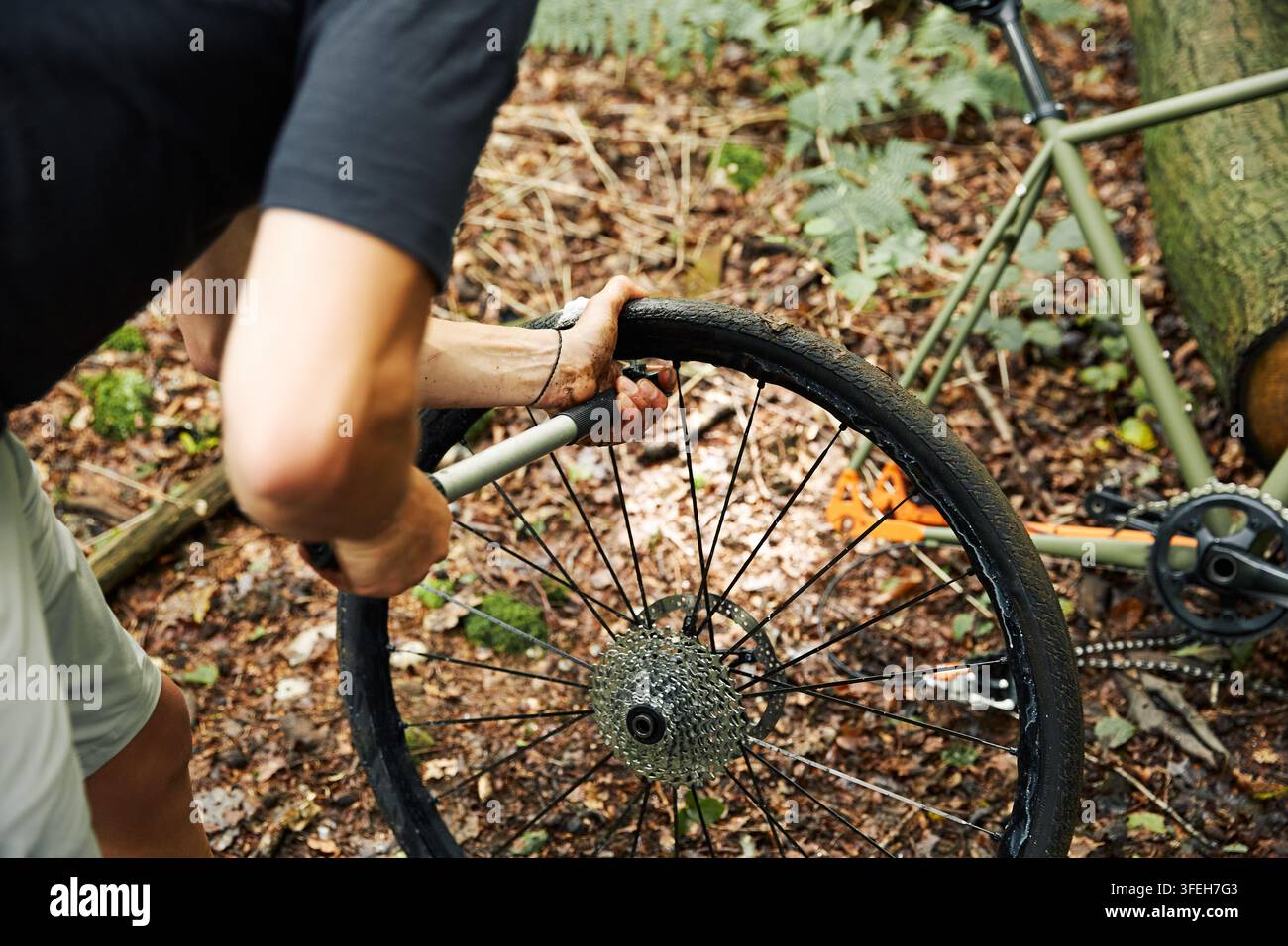 Cycliste réparant une crevaison sur un sentier forestier Banque D'Images