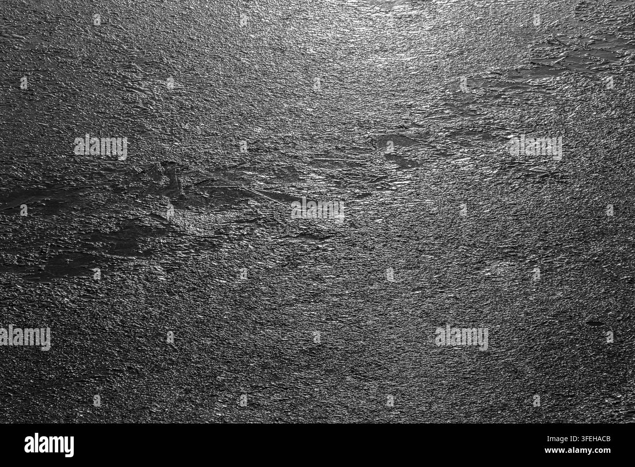 Texture abstraite noir et blanc à contraste élevé d'ice rugueux et scintillant sur une surface de lac gelée en hiver. Banque D'Images