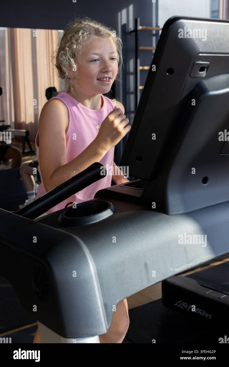 Une fille blanche de dix ans courant sur un tapis de course dans une salle de sport Banque D'Images
