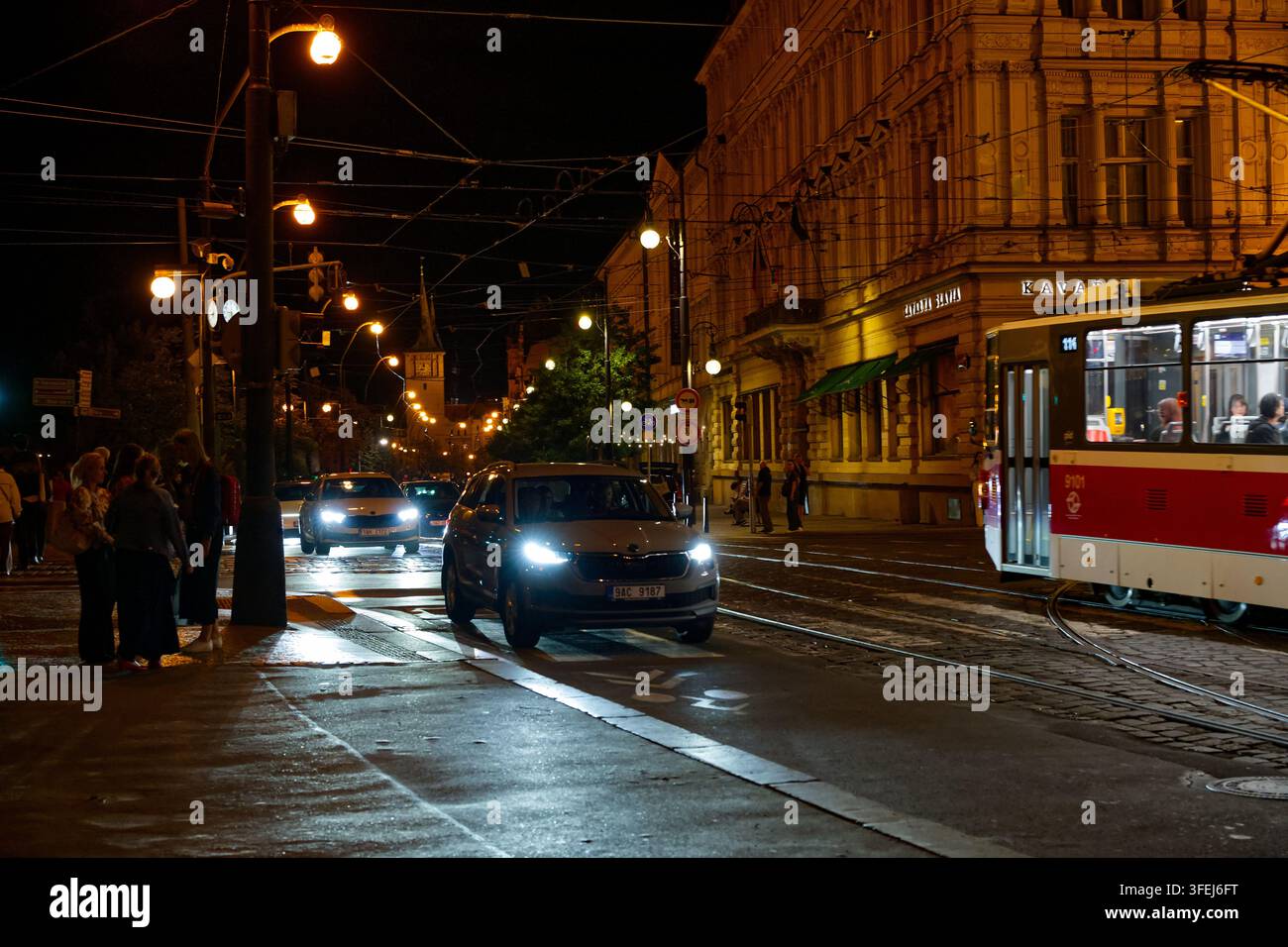 La circulation nocturne et un tramway de Prague passent devant le café historique Slavia sur les quais Masaryk près du Théâtre national. Banque D'Images