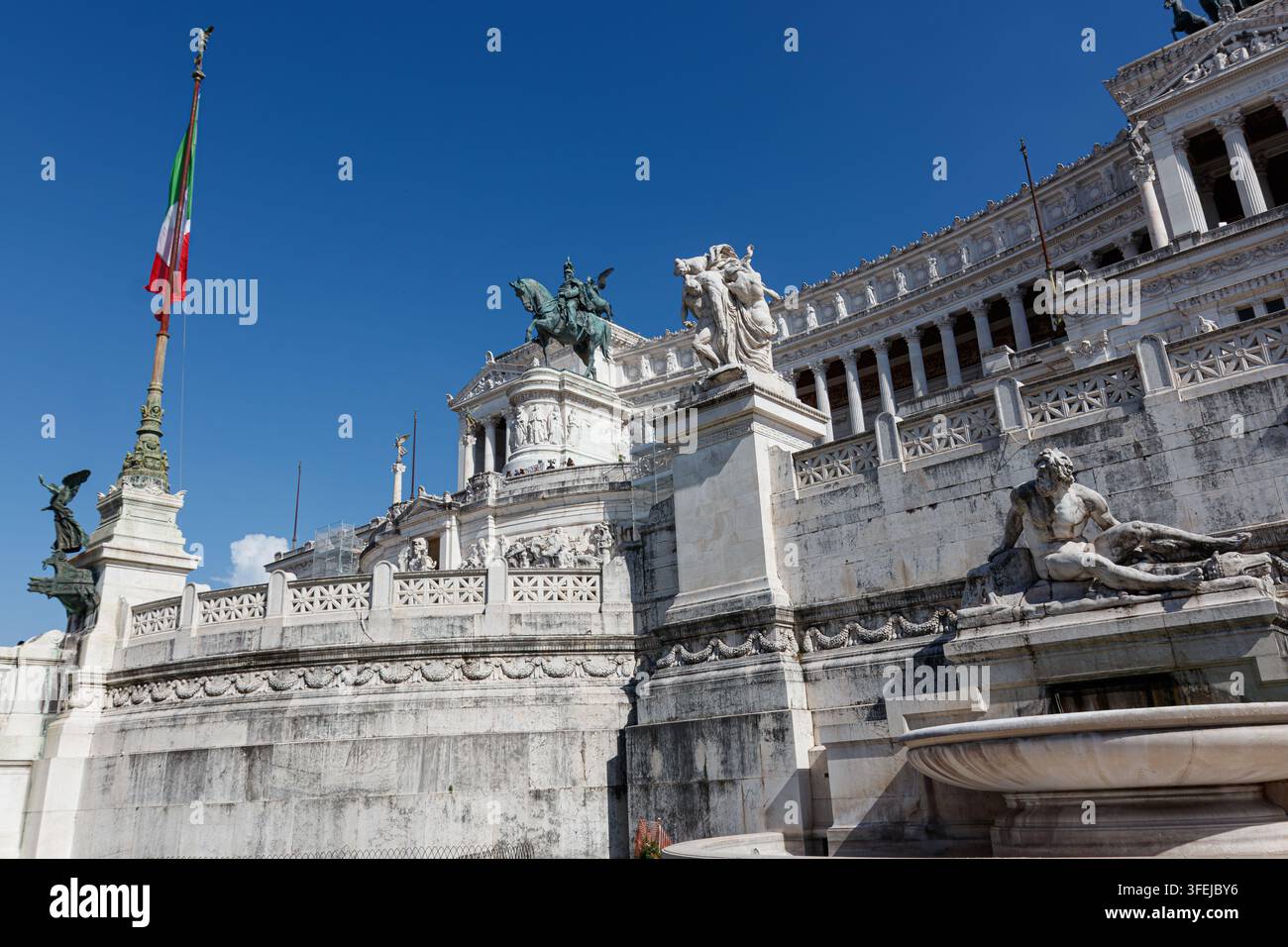 Vue large du Monument national Victor Emmanuel II Vittoriano avec drapeau italien et statues de marbre sous un ciel bleu à la Piazza Venezia, Rome, Italie Banque D'Images