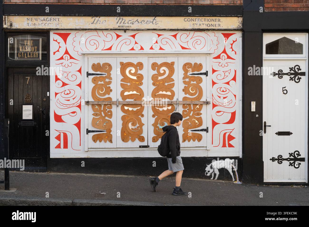 Un garçon passe devant la Mascot Gallery sur Church Hill à Ramsgate, dans le Kent, explorant l'art de rue unique de la ville balnéaire. Banque D'Images