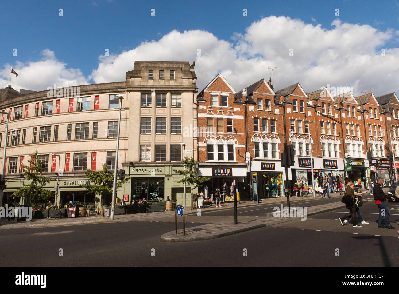Les clients passent devant les supermarchés Revolution et Party sur Lavender Hill à Clapham Junction, à Londres, profitant d'une journée ensoleillée. Banque D'Images