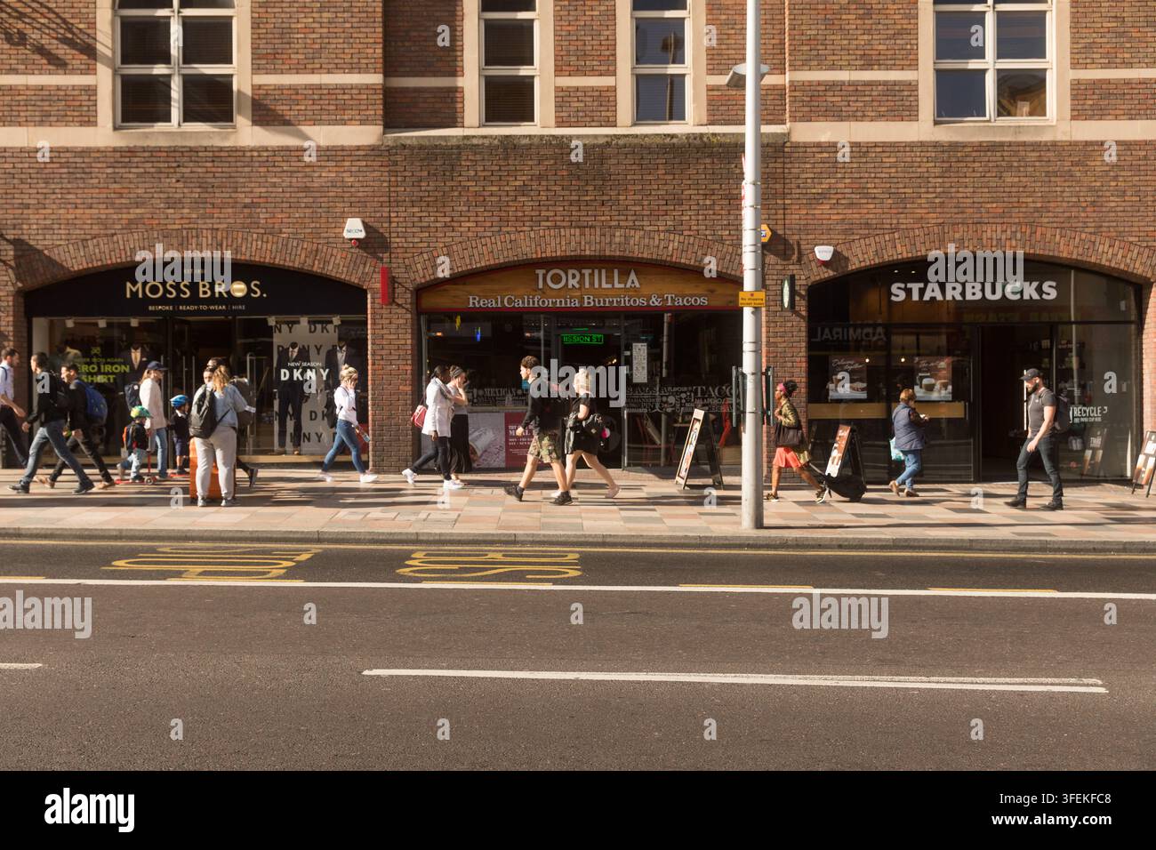 Les piétons marchent le long de St John's Hill devant Moss Bros, Tortilla et Starbucks, faisant la navette et faisant leurs courses par une journée ensoleillée. Banque D'Images