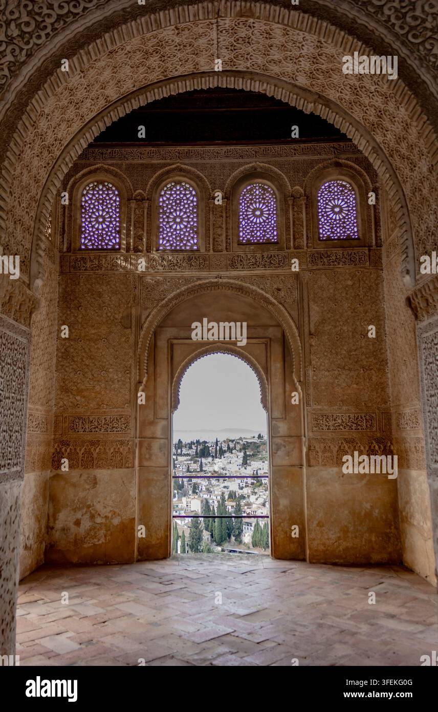 Arche en stuc islamique complexe et fenêtres encadrant une vue sur Albaicin depuis les palais nasrides de l'Alhambra, en Espagne Banque D'Images