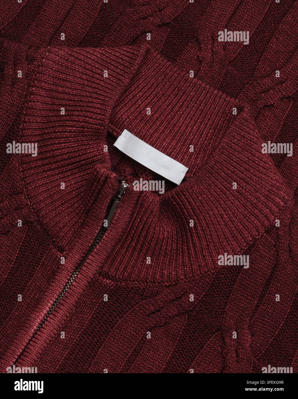 Grossissement d'un pull en tricot torsadé bordeaux avec col mock côtelé et demi-fermeture éclair. Détail vestimentaire en studio pour usage catalogue et commerce électronique. Banque D'Images