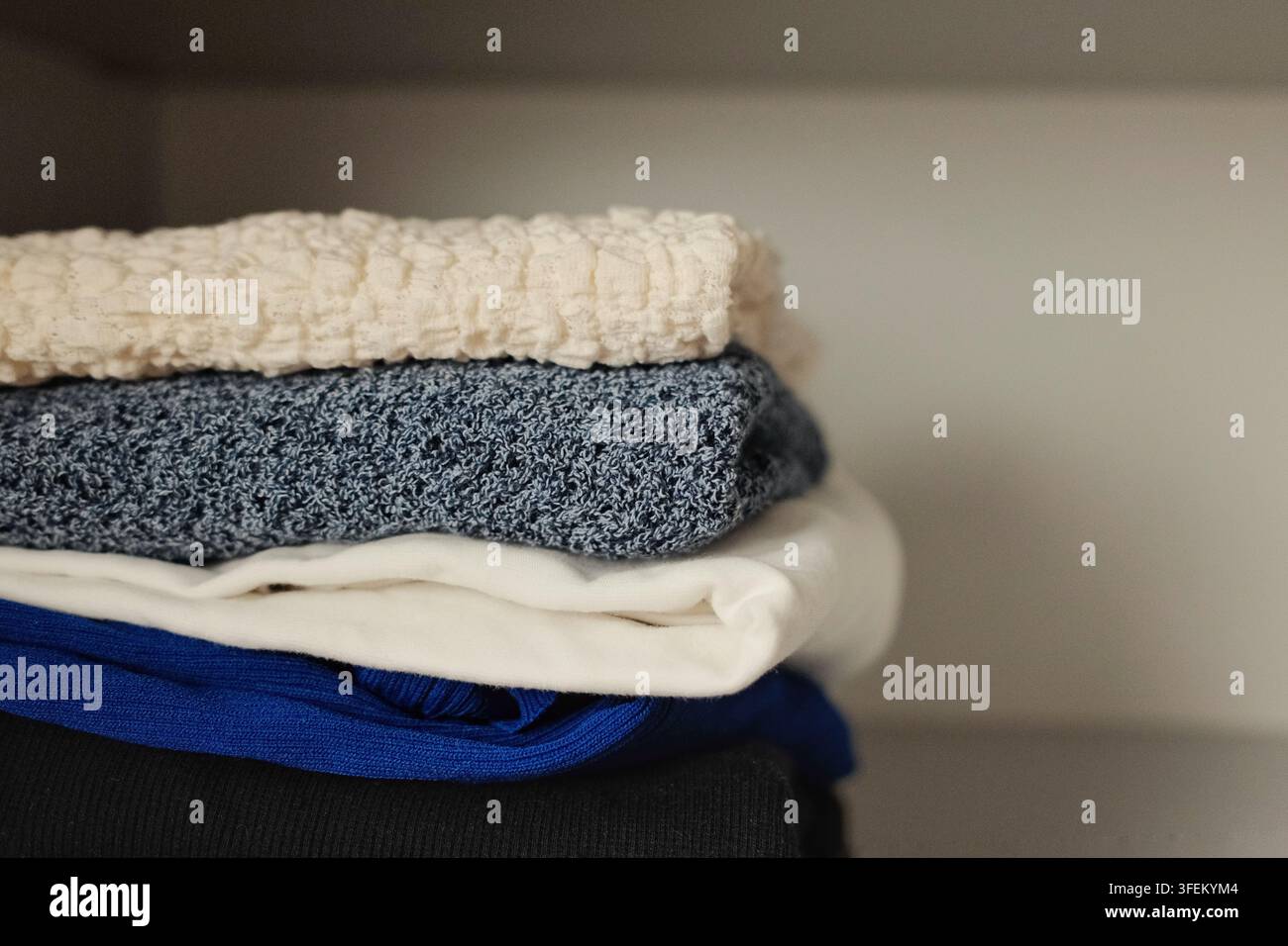Pile soigneusement pliée de pulls chauds dans une armoire propre, mettant en évidence le rangement organisé des vêtements et la préparation pour la saison automnale et hivernale Banque D'Images