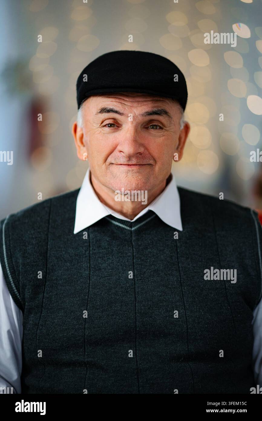 Homme âgé souriant portant une casquette et un gilet en sweat Banque D'Images