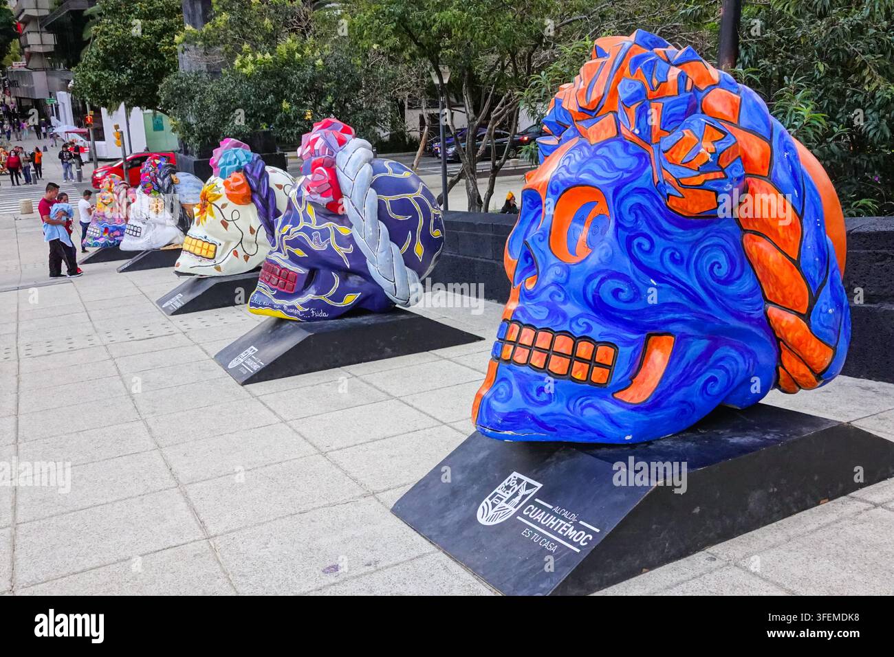 Les gens s'arrêtent pour contempler une exposition de crânes géants décorés par des artistes célébrant le festival annuel de la Journée des Morts sur la Plaza de la Révolution, le 31 octobre 2022 à Mexico, au Mexique. La Journée des Morts est une fête traditionnelle célébrée à travers le Mexique pour se souvenir de ceux qui sont morts de manière amusante et festive. Banque D'Images