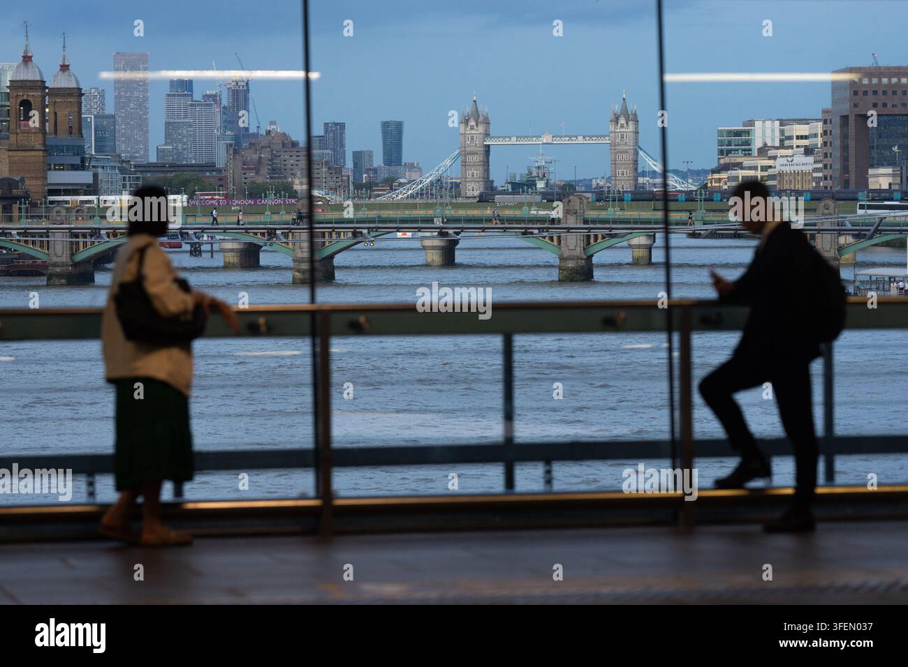 Les navetteurs s'arrêtent à la gare de Blackfriars avec vue sur la Tamise, profitant des vues de Tower Bridge pendant leur trajet du soir. Banque D'Images