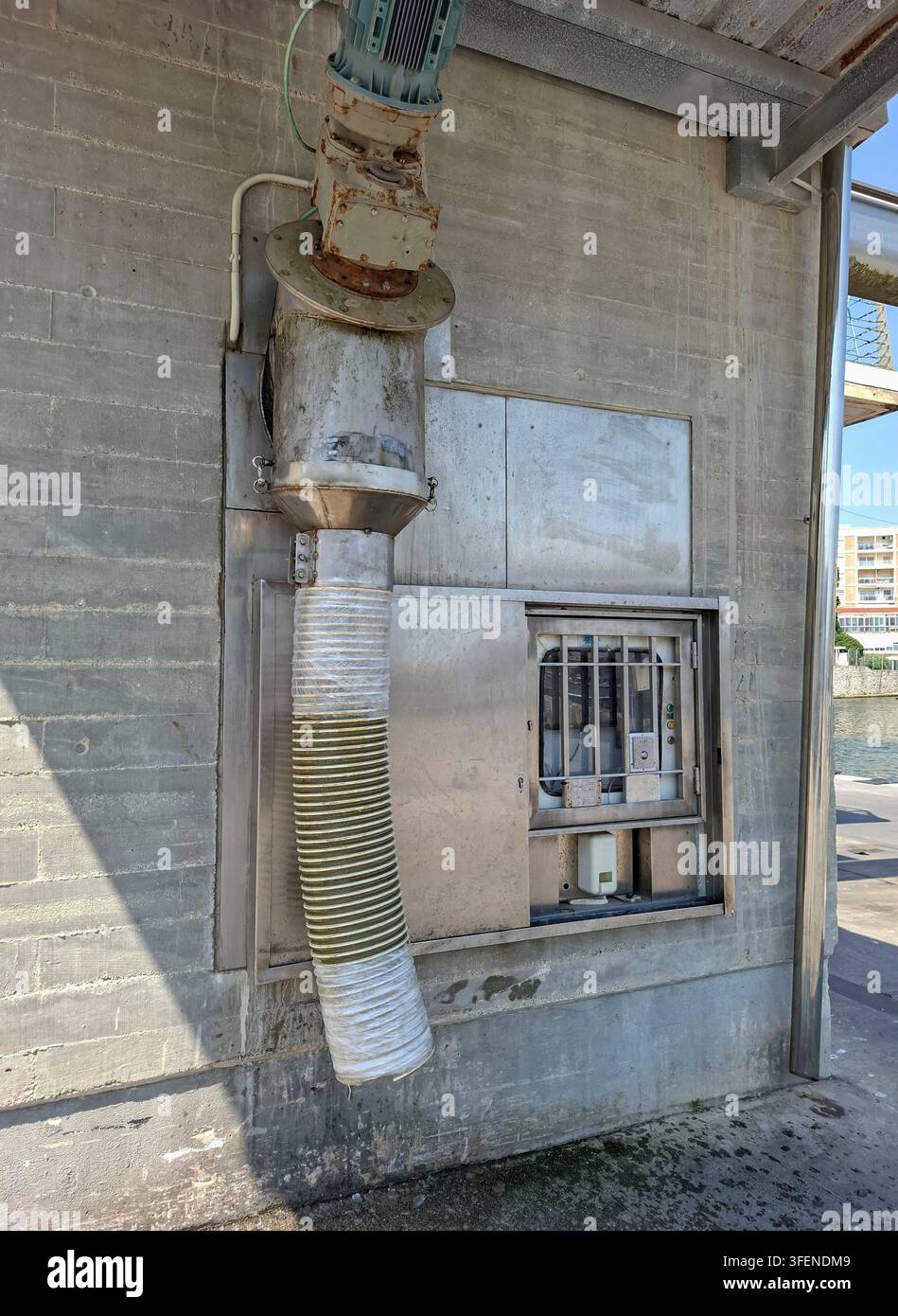 La station de livraison de glace du port montre l'assemblage du moteur, la trémie d'alimentation et le panneau de contrôle montés sur un mur en béton. La rampe suspendue dirige i Banque D'Images