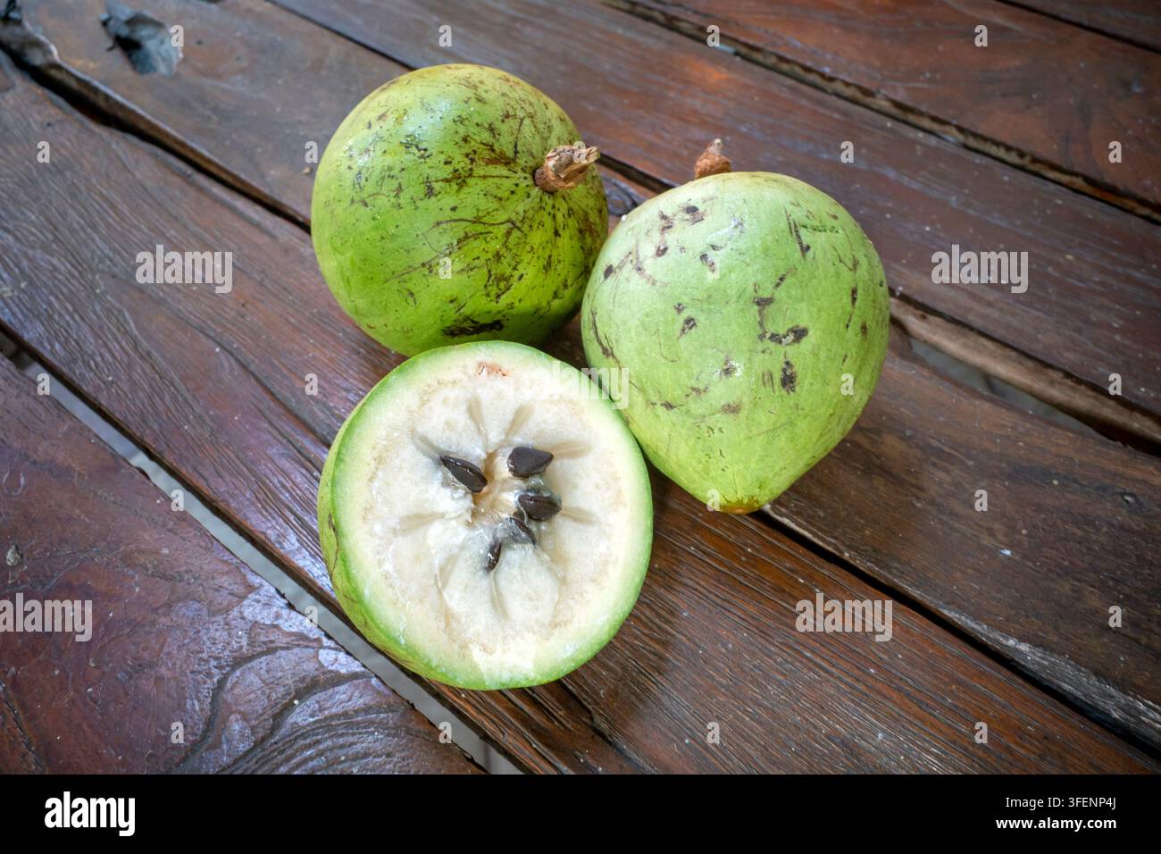 Pomme verte fraîche en forme d'étoile, Caimito (Chrysophyllum cainito) fruits entiers et demi-section montrant les graines sur fond en bois. Banque D'Images