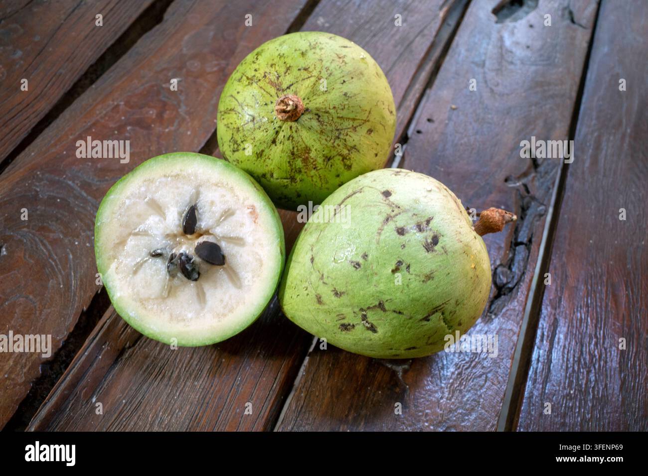 Pomme verte fraîche en forme d'étoile, Caimito (Chrysophyllum cainito) fruits entiers et demi-section montrant les graines sur fond en bois. Banque D'Images
