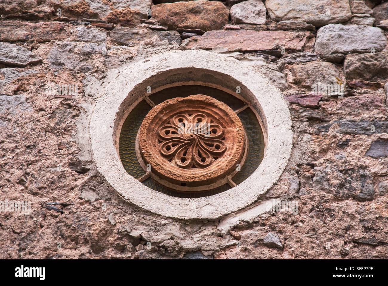 Grossissement d'un vitrail en pierre sur la façade d'une vieille maison médiévale dans la ville de Castelnau-Pégayrols Banque D'Images