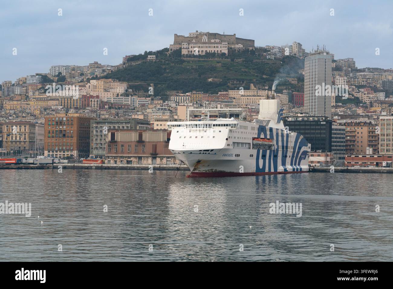 Une ferry GNV est amarrée au port de Naples, en Italie, pour le transport de passagers sous le monument du Castel Sant'Elmo situé au sommet de la colline. Banque D'Images