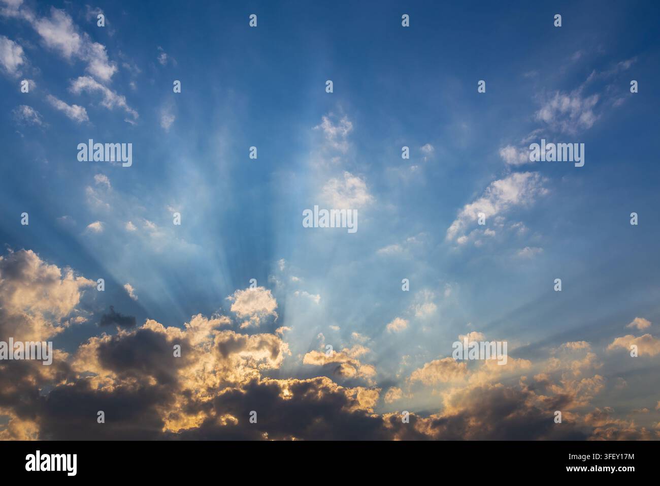 Ciel nuageux pendant le coucher du soleil avec des rayons de soleil cachés derrière les nuages. Banque D'Images